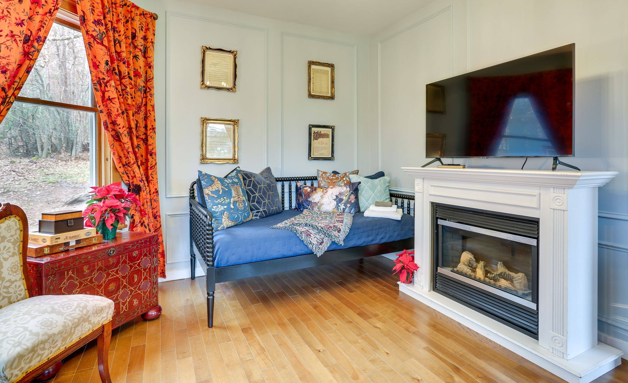 A spindle daybed beside the fireplace in the living room, made up with layered pillows.