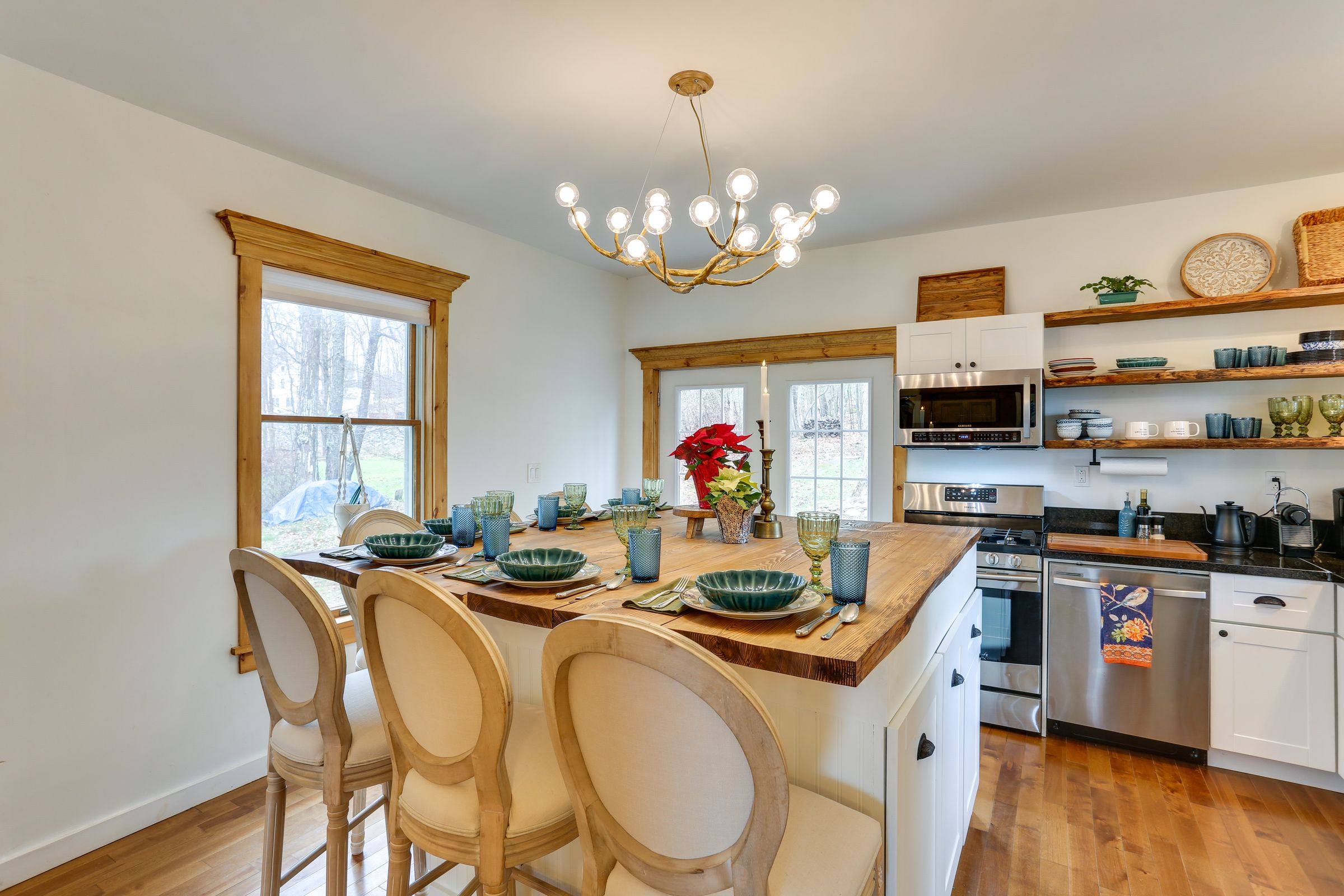 The butcher-block kitchen island set for dinner for four under a branching brass chandelier.