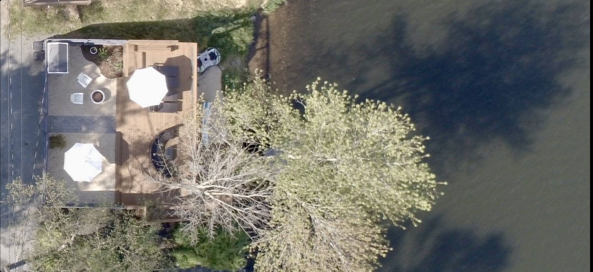 Overhead view of the private lake deck, umbrellas and seating reaching out over the open water.