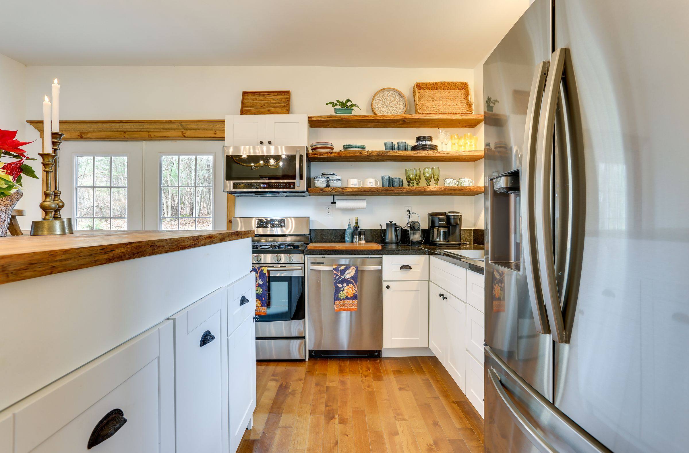 The fully equipped kitchen with gas range, open wood shelving and stone counters.