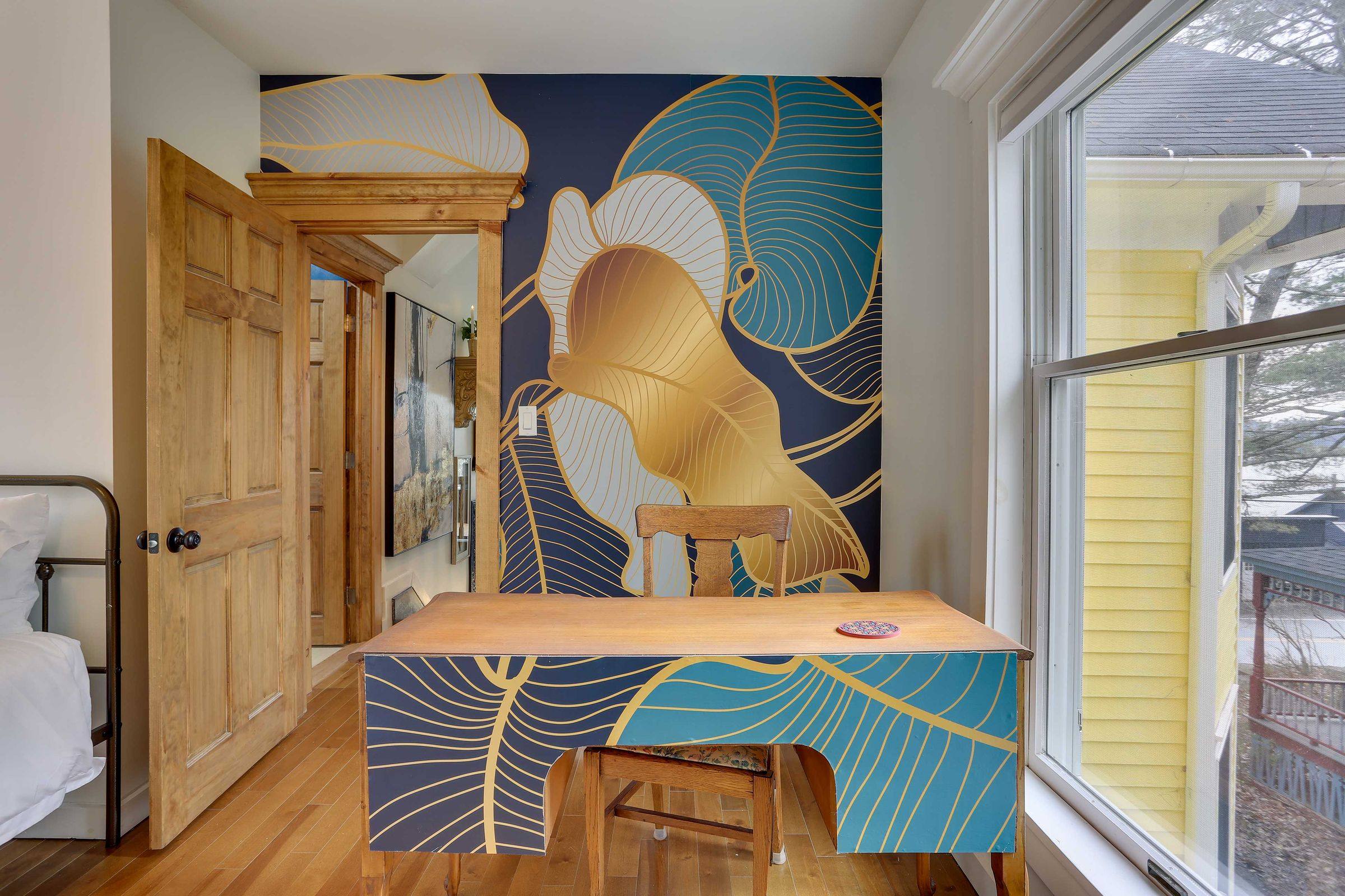 The dedicated workspace: a desk set against a hand-painted navy and gold mural.